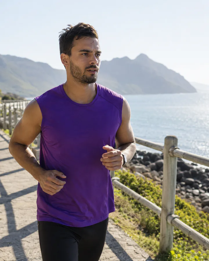 Runner in a purple top exercising by the coast