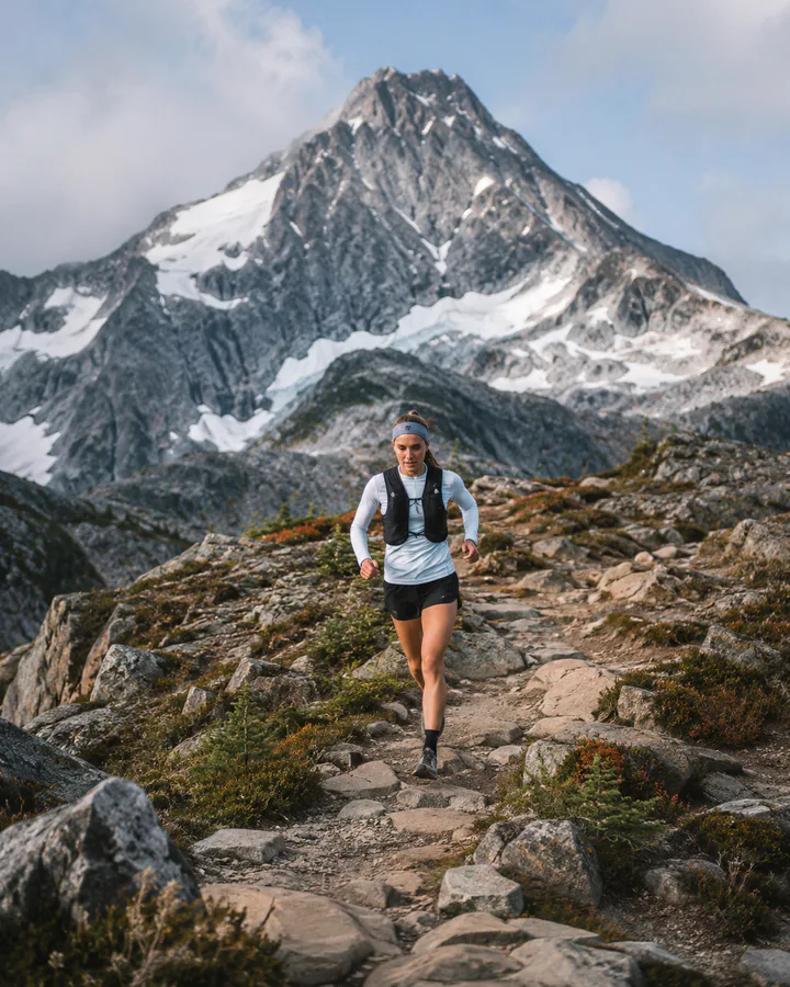Trail runner crossing a dramatic mountain landscape